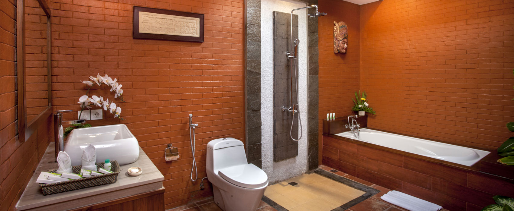 Modern ensuite bathroom at Kanti Garden Villa with a white bathtub and red brick walls.