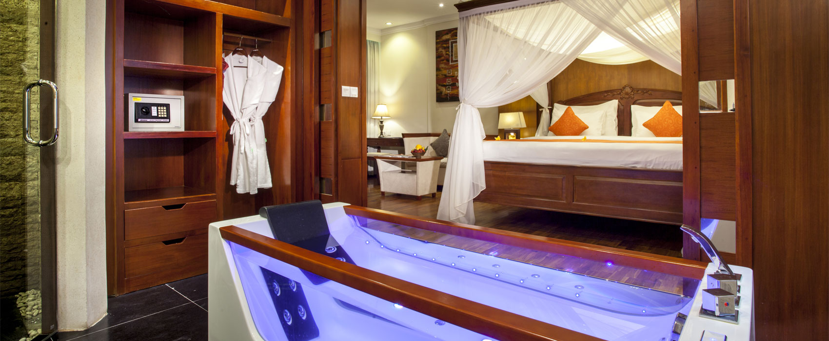 Luxury Suite Room bedroom at Astagina Resort & Spa Bali, featuring a private canopy bed and open bathroom with a jacuzzi.