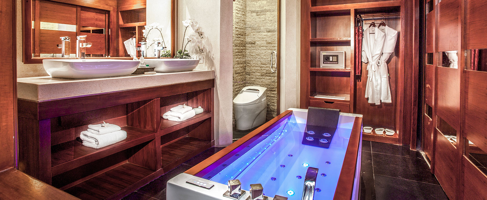 Luxury suite bathroom at Astagina Resort featuring a modern blue-lit jacuzzi bathtub.
