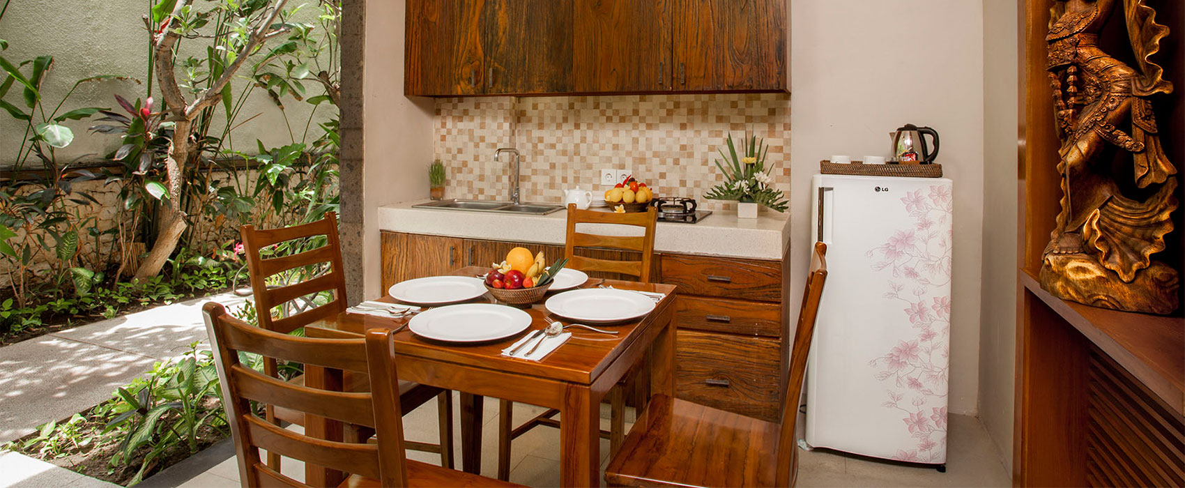 Cozy villa dining area with a wooden table set for four and a modern kitchenette at Astagina Resort.