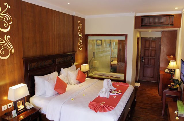 Romantic honeymoon bed decoration with towel swans in the warm Deluxe Terrace room at Astagina Resort.