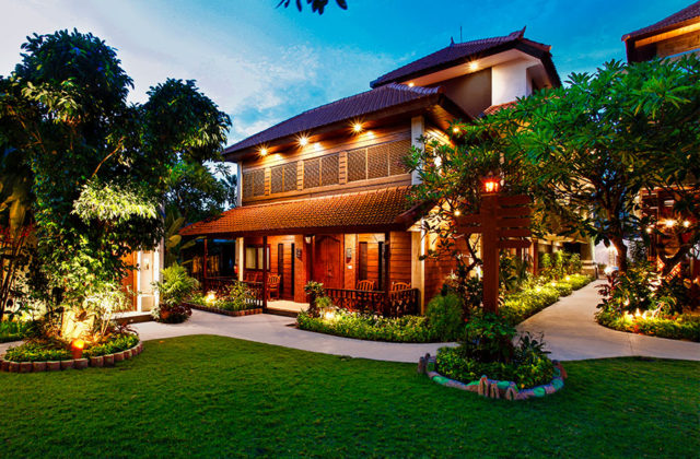 Exterior view of the one-bedroom villa featuring warm wooden architecture and lush greenery at Astagina Resort.