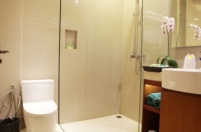 Modern bathroom facility featuring a walk-in shower with glass enclosure, toilet, and vanity sink.