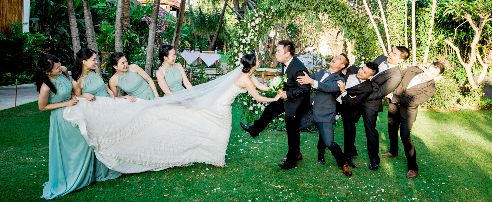 Bride and groom sharing a fun moment with bridesmaids and groomsmen outdoors at Astagina Resort