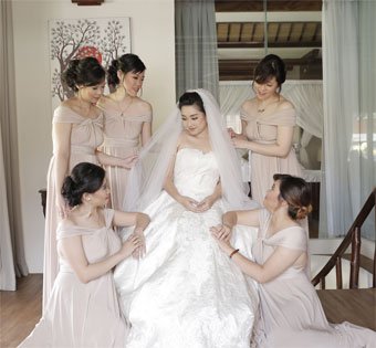 A beautiful bride in a white gown surrounded by bridesmaids in elegant blush dresses.