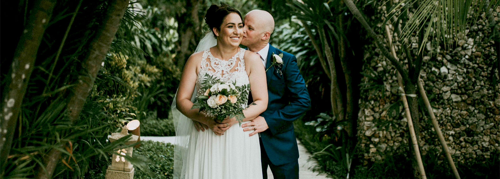 Happy bride and groom embracing in a lush tropical garden at Astagina Resort.