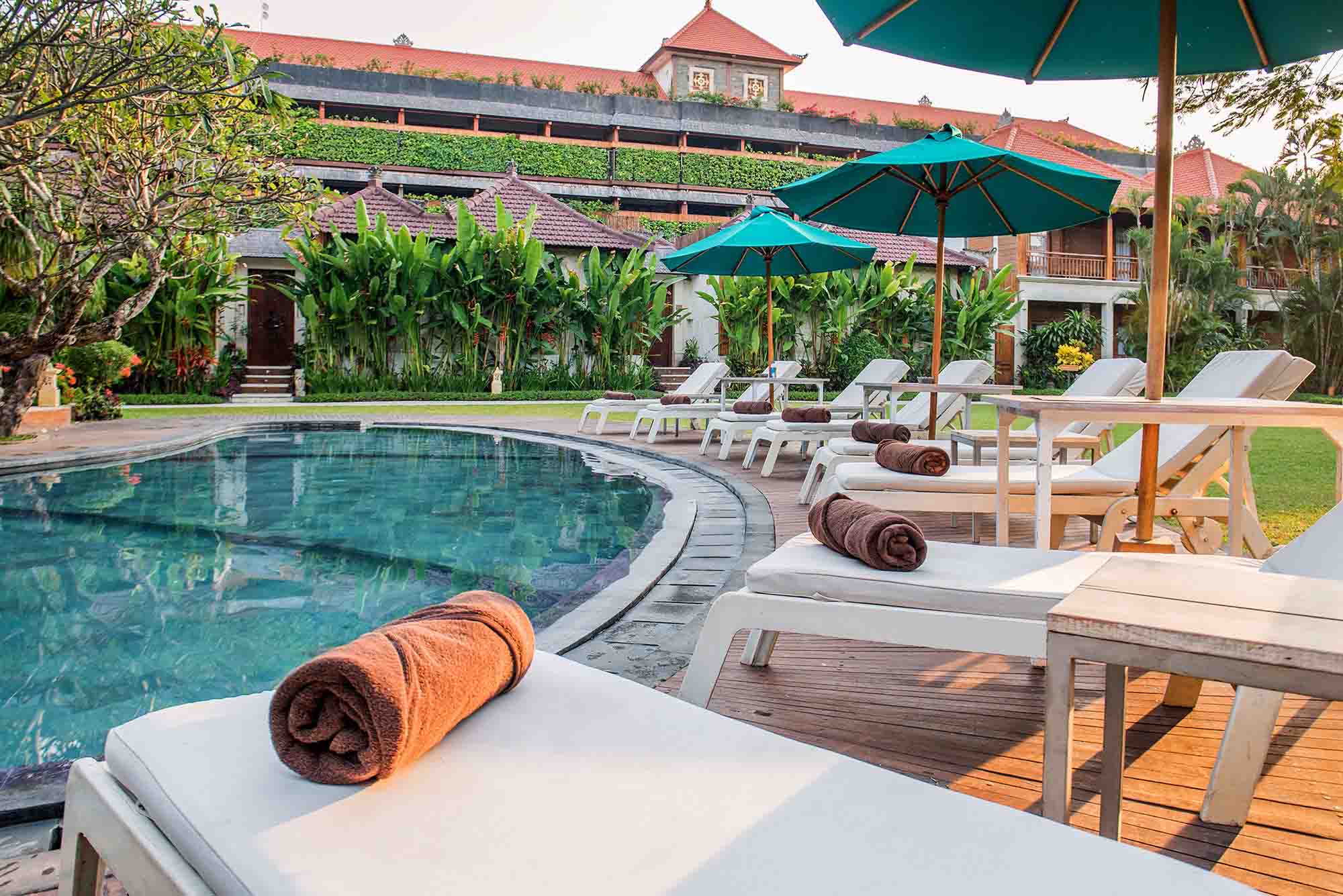 Kids' pool area at Astagina Resort with lounge chairs and teal umbrellas.