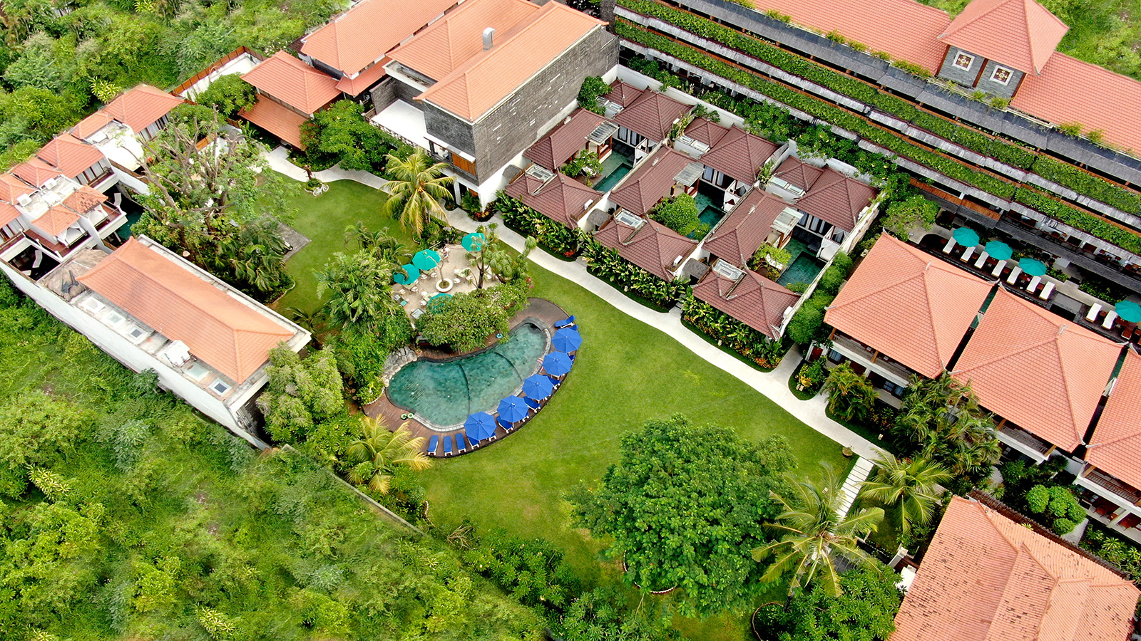 Aerial view of Astagina Resort & Spa Bali main garden, featuring luxury tropical landscaping, outdoor swimming pool, and villa architecture.