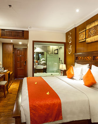 Elegant Deluxe Room at Astagina Resort with Balinese wooden accents.