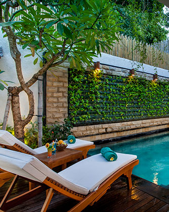 Private plunge pool at Astagina Resort with wooden sun loungers.