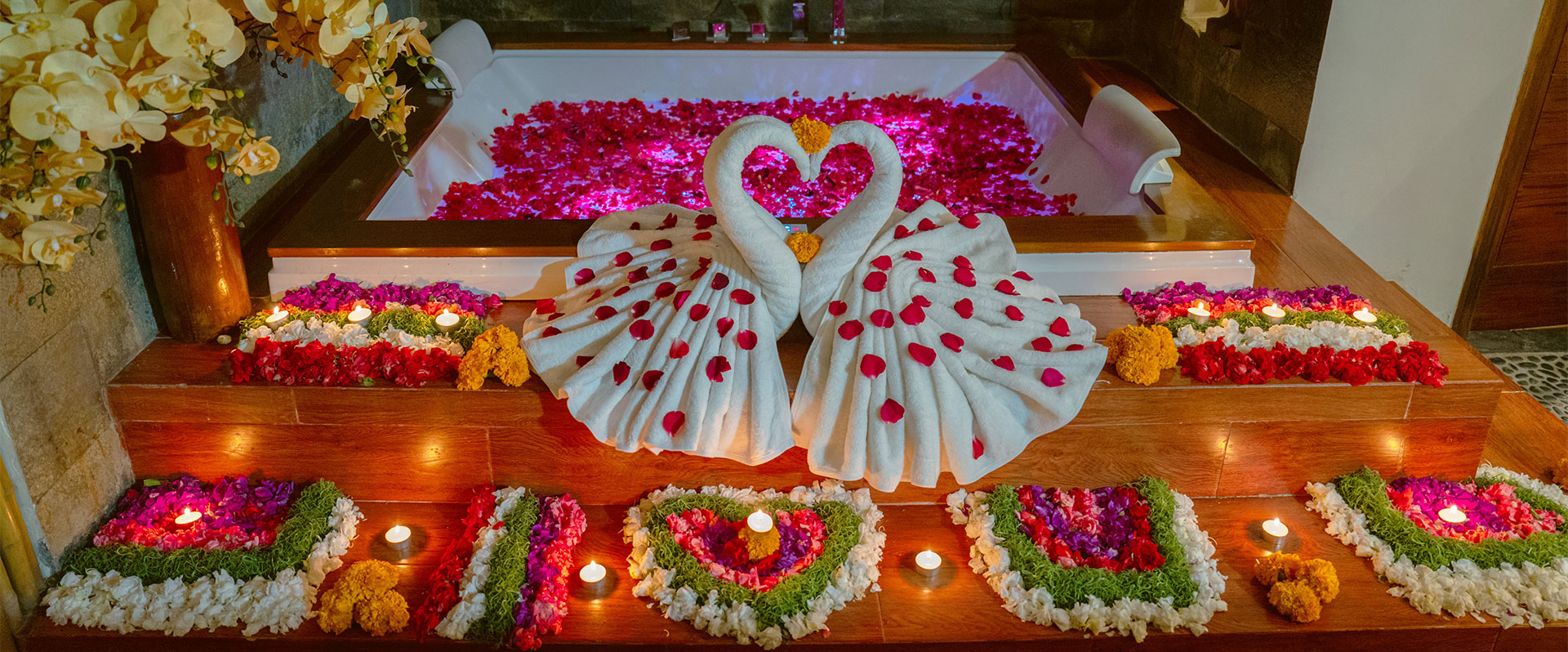 Luxury spa jacuzzi decorated with vibrant flower petals and towel swans at Anjali Spa