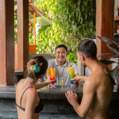 Guests enjoying cocktails at the pool bar of Astagina Resort Legian, highlighting relaxed resort facilities and added stay value.