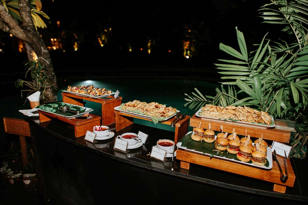 Event catering food station at night by the resort pool.