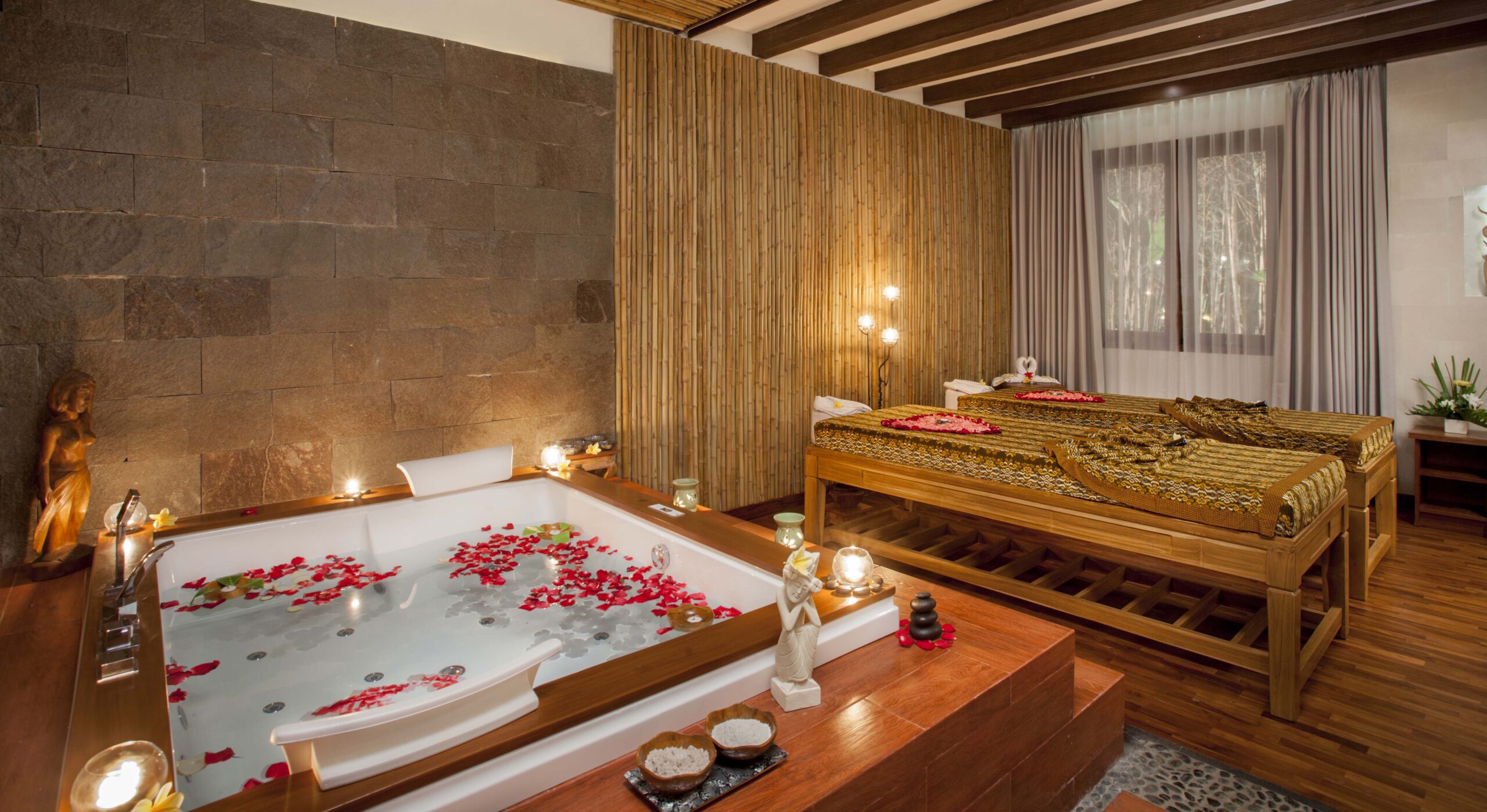 A luxurious spa room at Astagina Resort with a bathtub filled with water and red rose petals