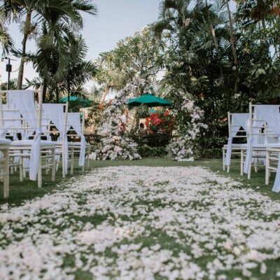 Garden wedding ceremony setup with white chairs, floral arch, and petal aisle at a Bali garden wedding venue in Astagina Resort Villa & Spa Legian