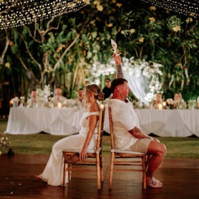 Evening garden wedding reception at Astagina Courtyard with fairy lights canopy, long dinner table setup, and couple playing wedding game during Bali garden wedding celebration at Astagina Resort Villa and Spa Legian