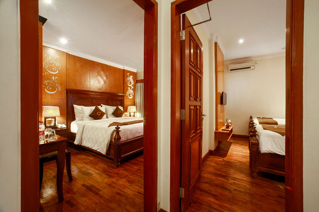 Two bedroom suite interior at Astagina Resort Bali featuring wooden design, connected rooms, and comfortable bedding for family stay
