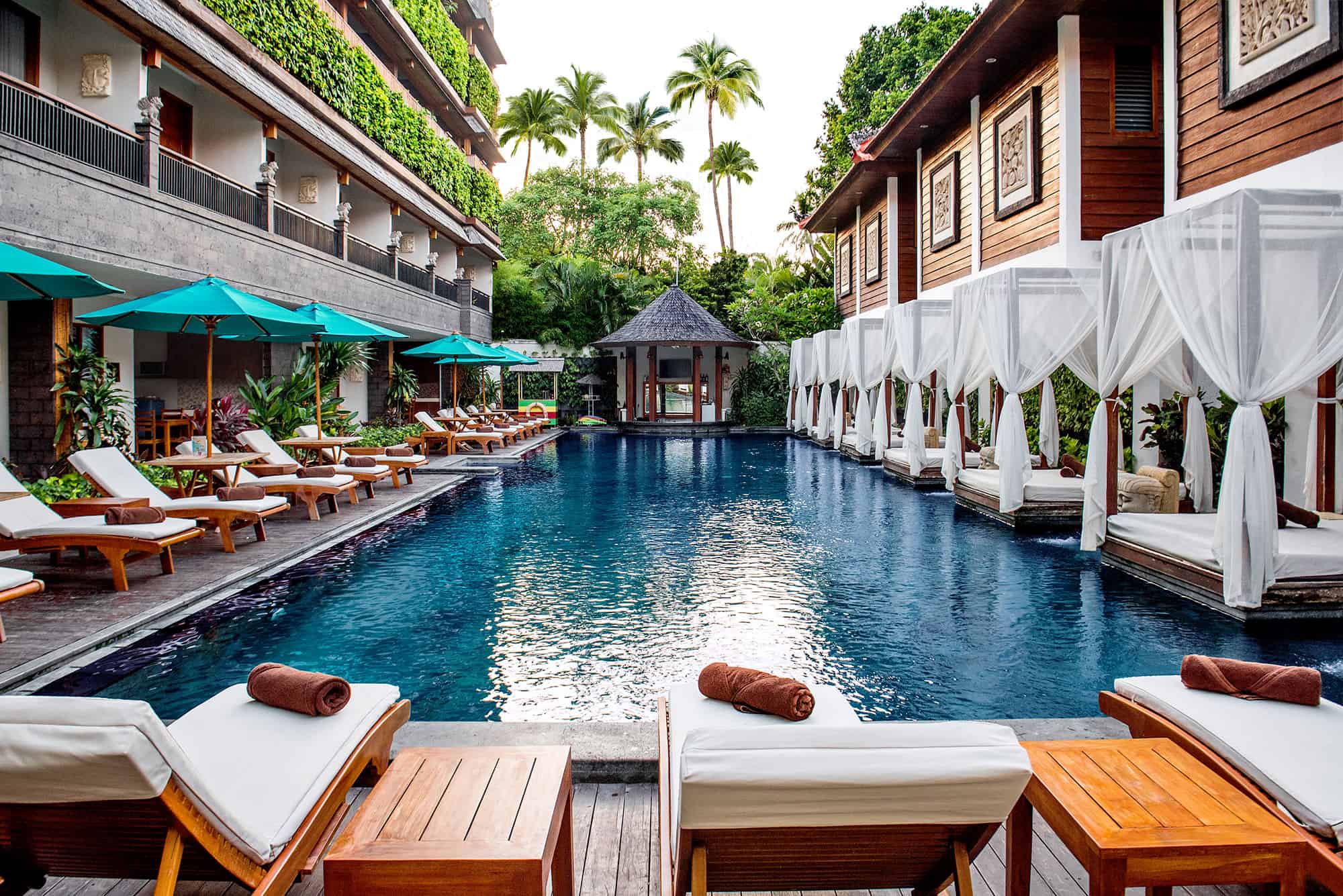 Main swimming pool at Astagina Resort with cabanas and tropical courtyard setting.