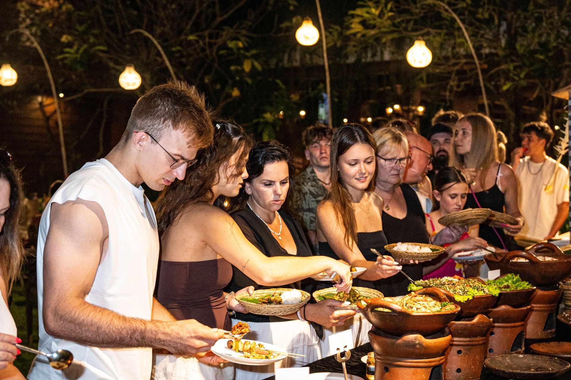 Guests enjoying a festive and warm outdoor Balinese Suckling Pig BBQ dinner at Astagina Resort