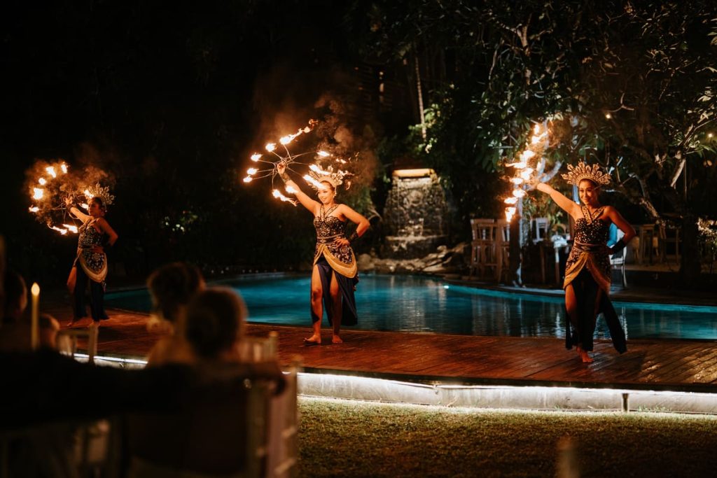 Balinese fire dancers performing poolside at a Bali garden wedding venue reception at Astagina Resort Legian