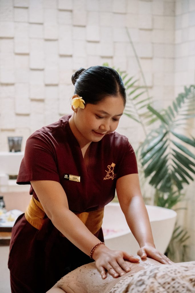Professional Anjali Spa therapist performing a traditional Balinese massage and body scrub at Astagina Resort Legian