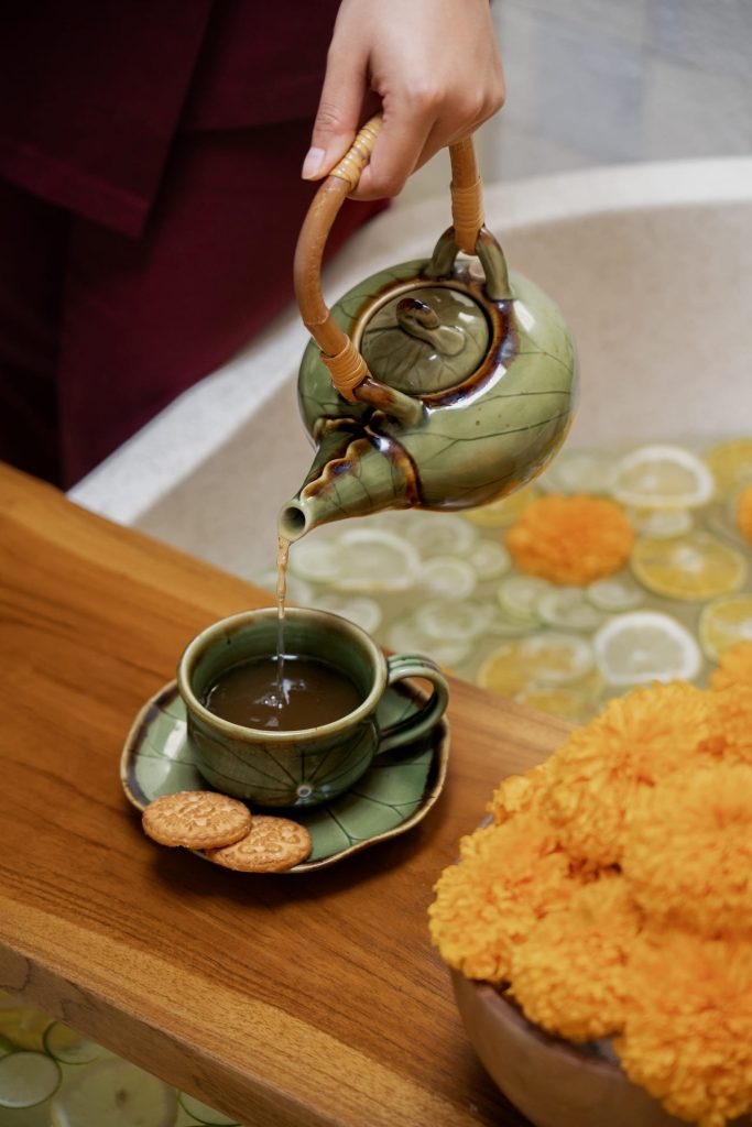 Therapist pouring refreshing herbal tea next to a tropical flower bath at Anjali Spa near Double Six Beach Legian