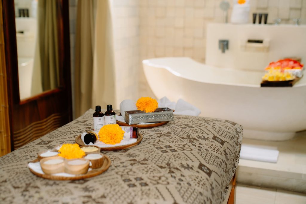 Natural Balinese spa setup featuring custom essential oils, sea salt scrubs, and marigold flowers at Anjali Spa Legian