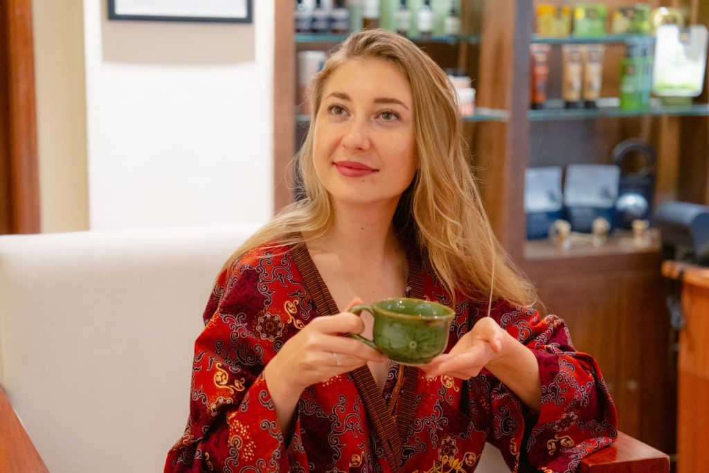 Guest enjoying post-treatment herbal tea in a batik kimono during a relaxation session at Anjali Spa Astagina Resort