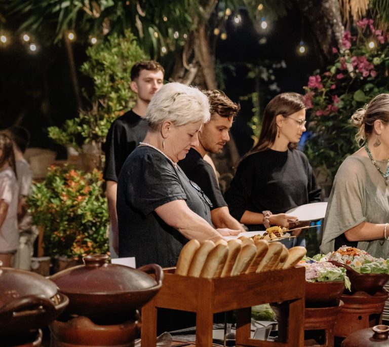 Guests lining up at the Balinese Night Buffet spread with bread and traditional dishes in the Banyan Garden, Astagina Resort