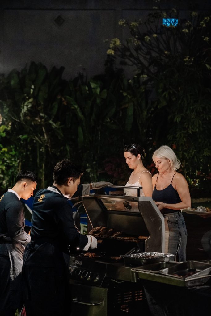Chefs grilling meat at the BBQ night station while resort guests watch, Pangi Bistro Legian Bali