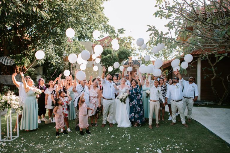 Intimate garden wedding celebration at Astagina Resort Bali with bride, groom, and guests releasing white balloons