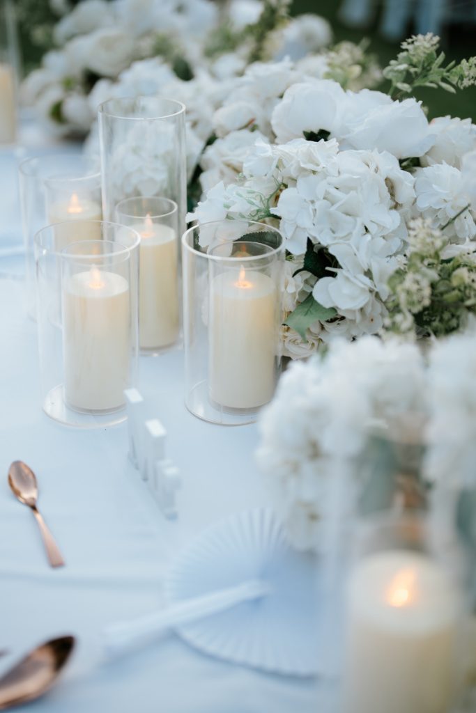 Candlelit white floral centerpieces along the reception table, Astagina garden wedding Legian